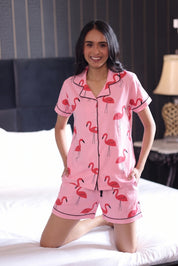 Woman wearing pink flamingo Shorts on a bed