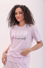 Woman wearing lavender oversized printed tee with ‘Be Kind to Yourself’ text by NapStory