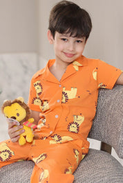Child wearing orange pajamas with lion-print animal patterns, holding a plush toy, sitting on a couch.