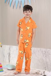 Child wearing orange pajamas with lion prints in a room setting.