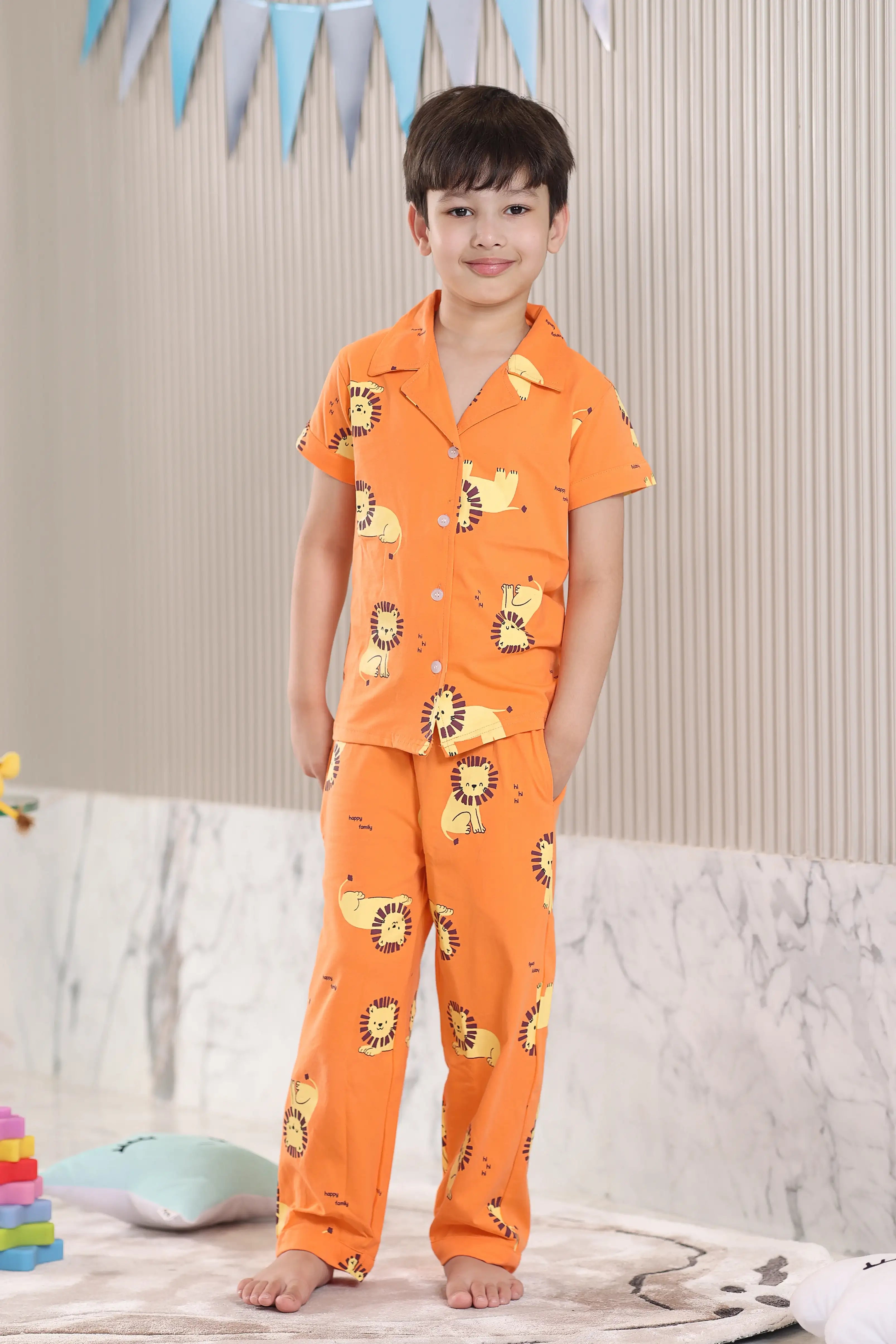 Child wearing orange pajamas with lion prints in a room setting.