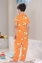 A child wearing an orange pajama set with lion prints in a living room.
