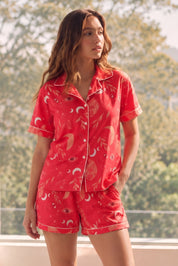 Woman wearing a red Shorts set with a floral pattern in a bright room.