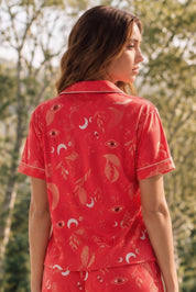 Woman wearing a red patterned shirt with nature in the background