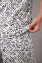 Patterned pants with a hand adjusting the drawstring on a neutral background