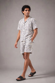 Man wearing a patterned shirt and shorts set on a gray background