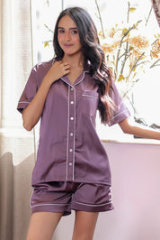 Woman wearing a purple shorts set with white trim in a bright room.