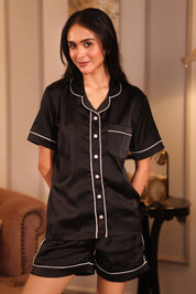 Woman wearing a black shorts set with white piping in a room setting.