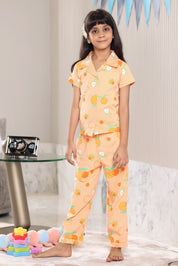 A girl wearing a matching Orange pajama set with an orange fruit pattern in a room.