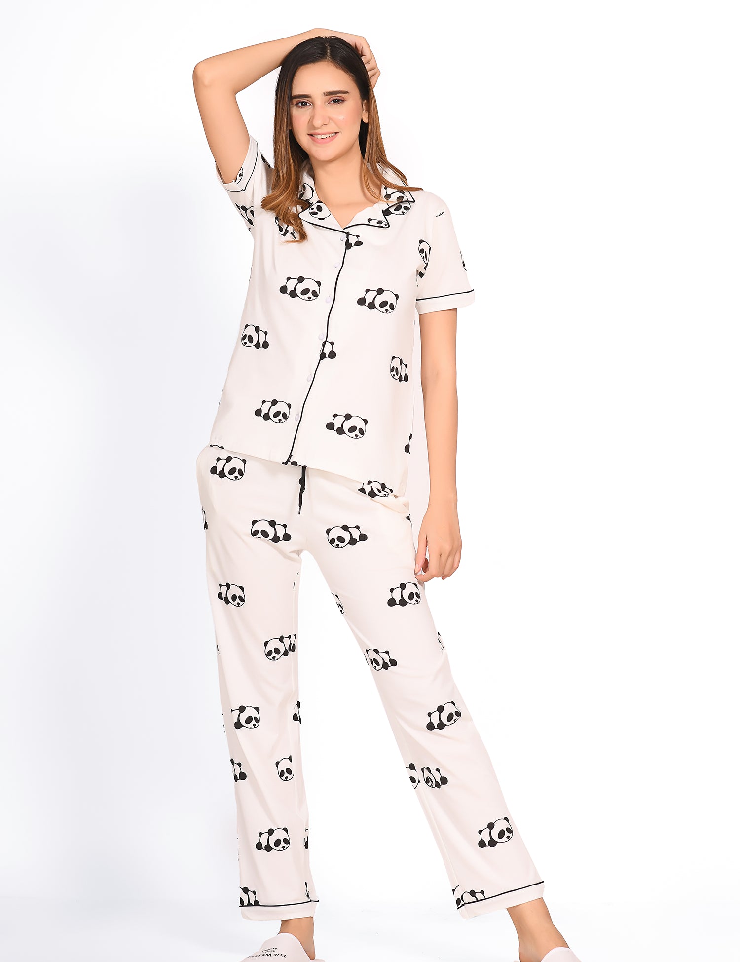 Young lady in a Panda Print Pyjama Set nightwear by NapStory, standing relaxed with her hand resting on her head.