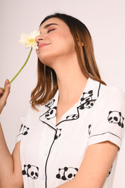 Young lady in a Panda Print Pyjama Set nightwear by NapStory, eyes closed, holding a flower, lost in thought.