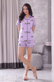 Woman wearing a purple shorts set with black and white patterns in a room.