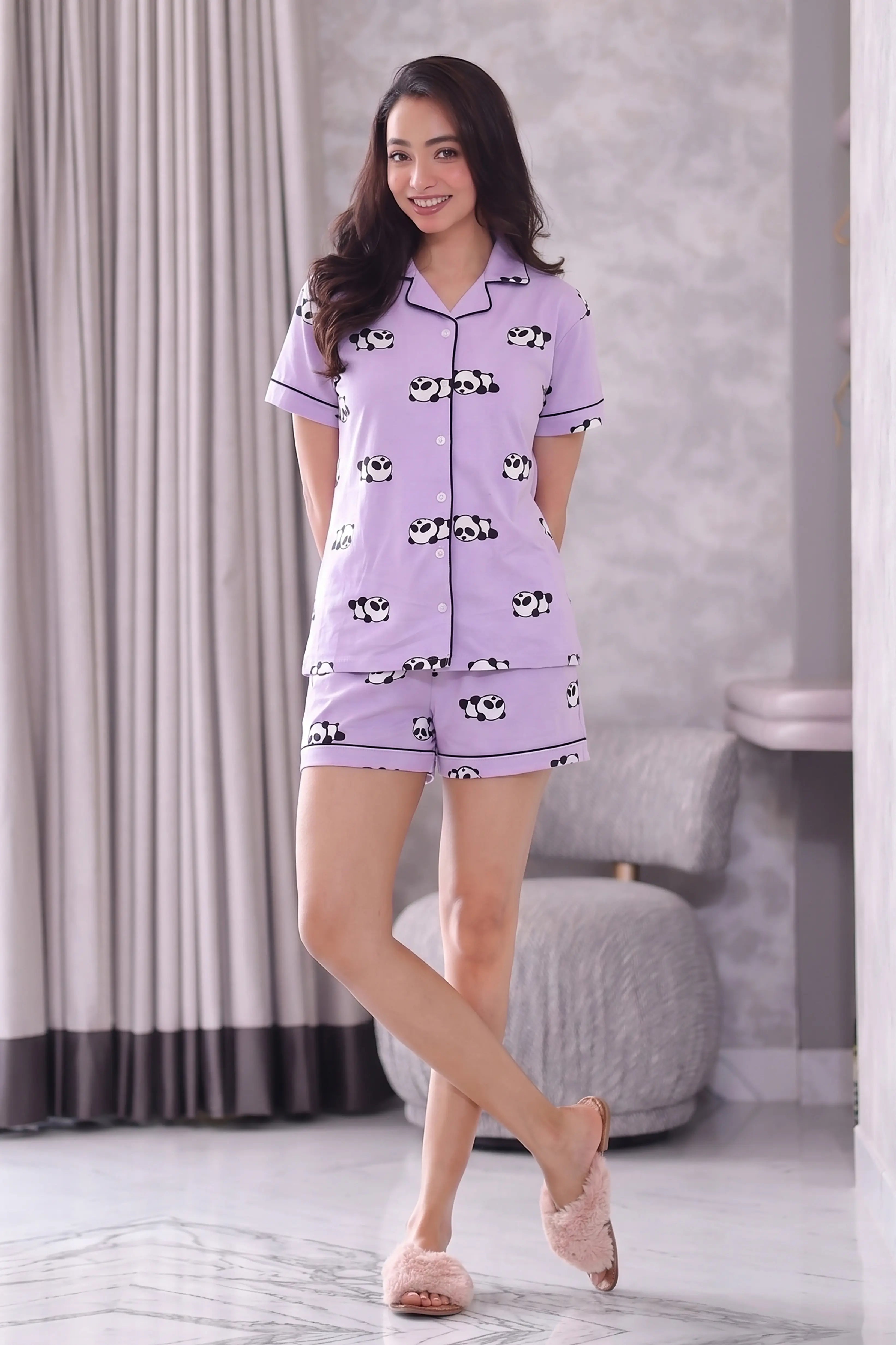 Woman wearing a purple shorts set with black and white patterns in a room.