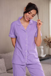 Woman wearing a purple pajama set in a living room.