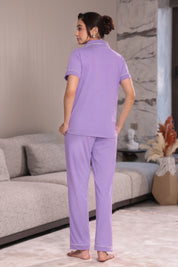 Woman wearing lavender pajamas standing in a modern living room.