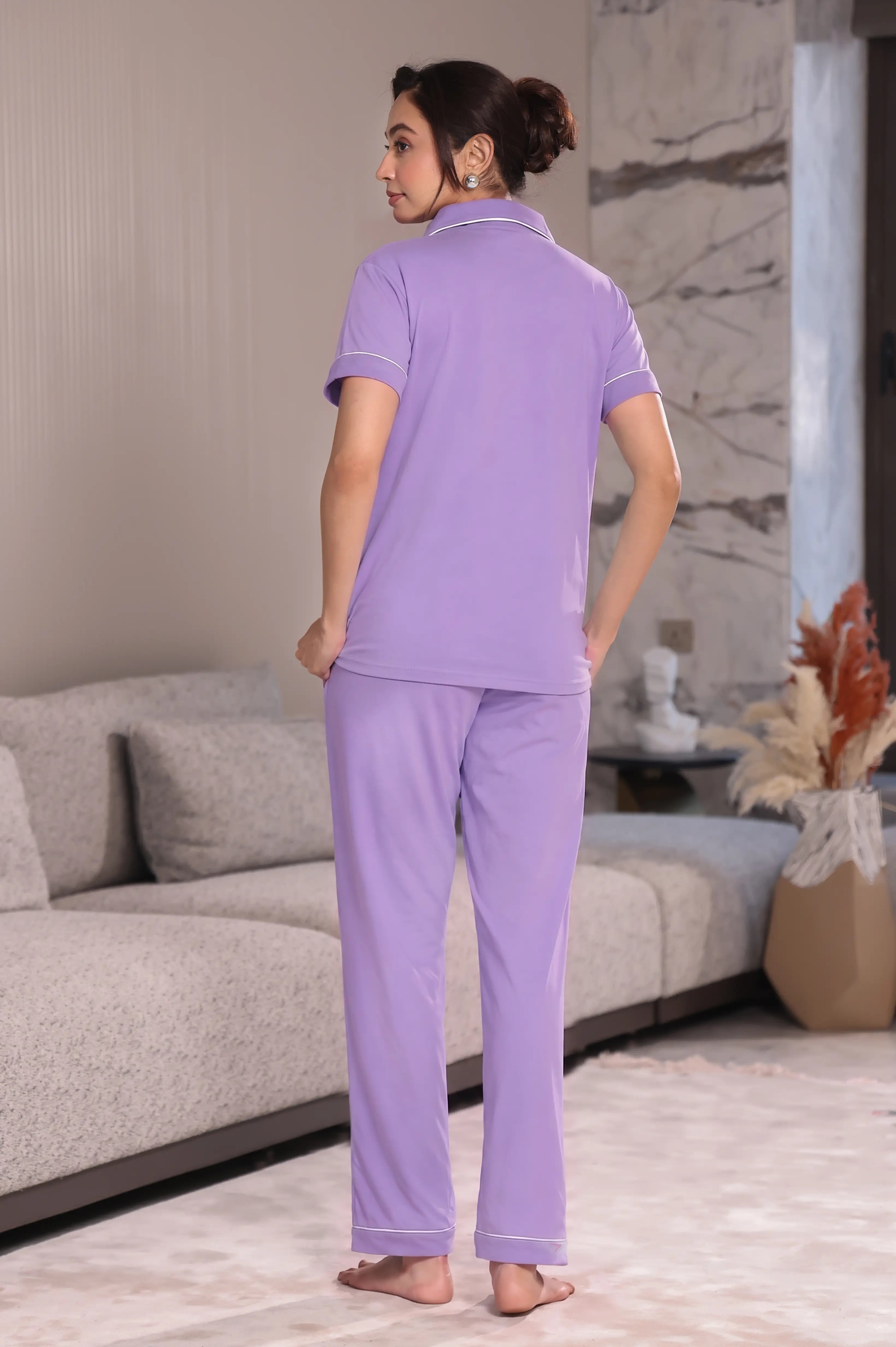 Woman wearing lavender pajamas standing in a modern living room.