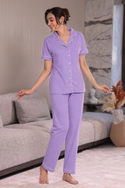 Woman wearing a purple pajama set in a living room.