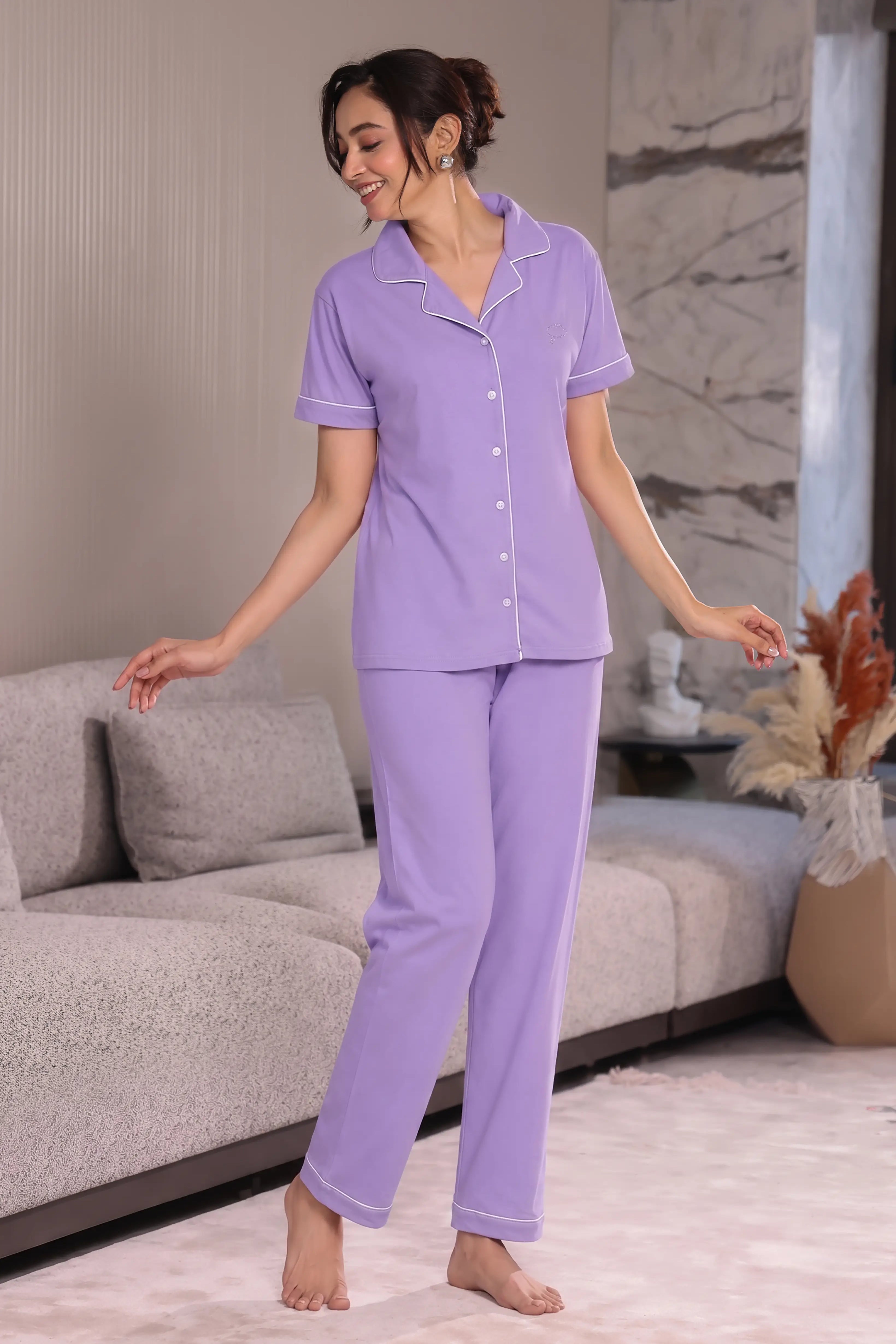 Woman wearing a purple pajama set in a living room.