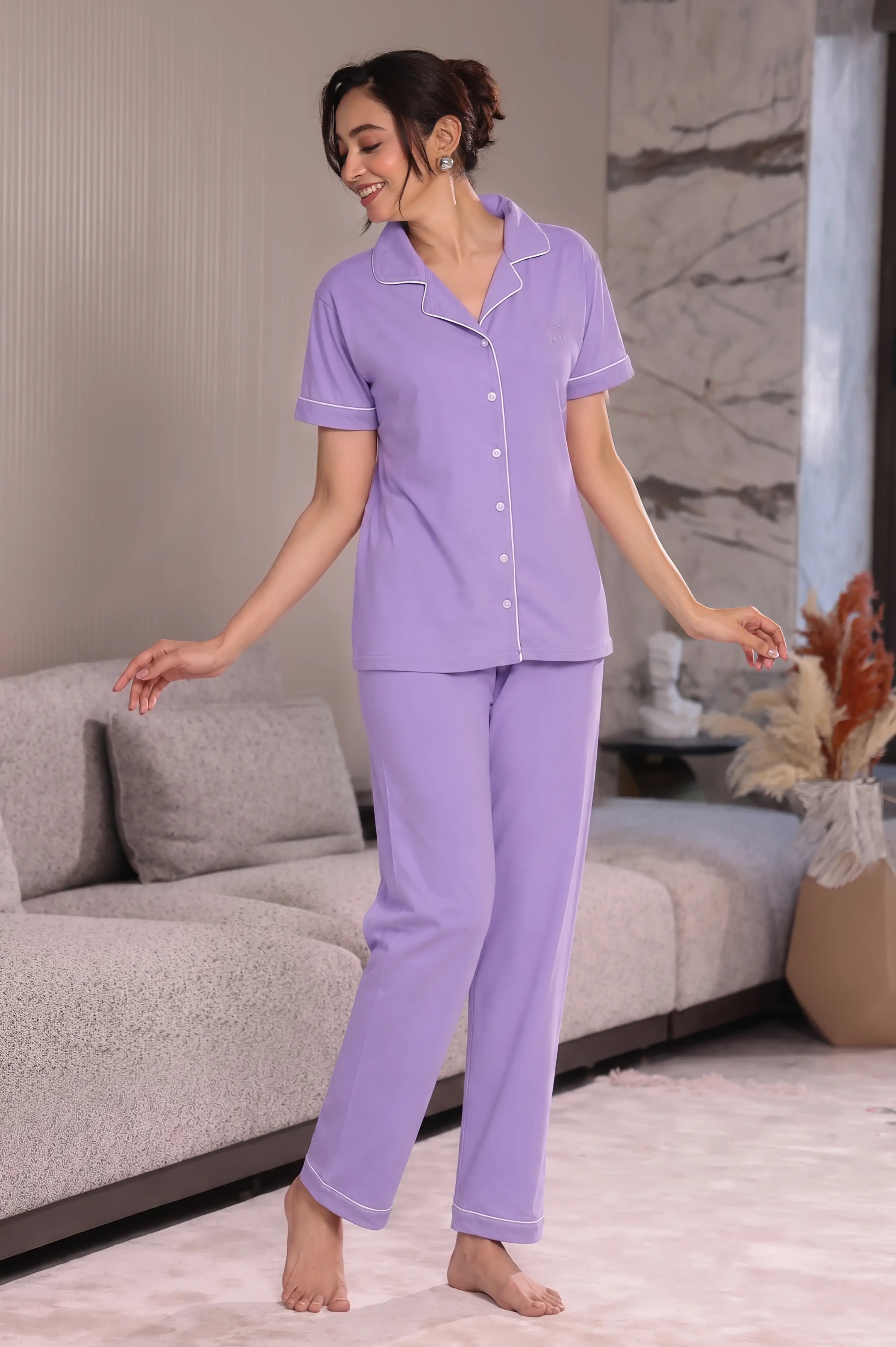 Woman wearing a purple pajama set in a living room.