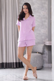 Woman wearing a light purple shorts set in a bathroom.