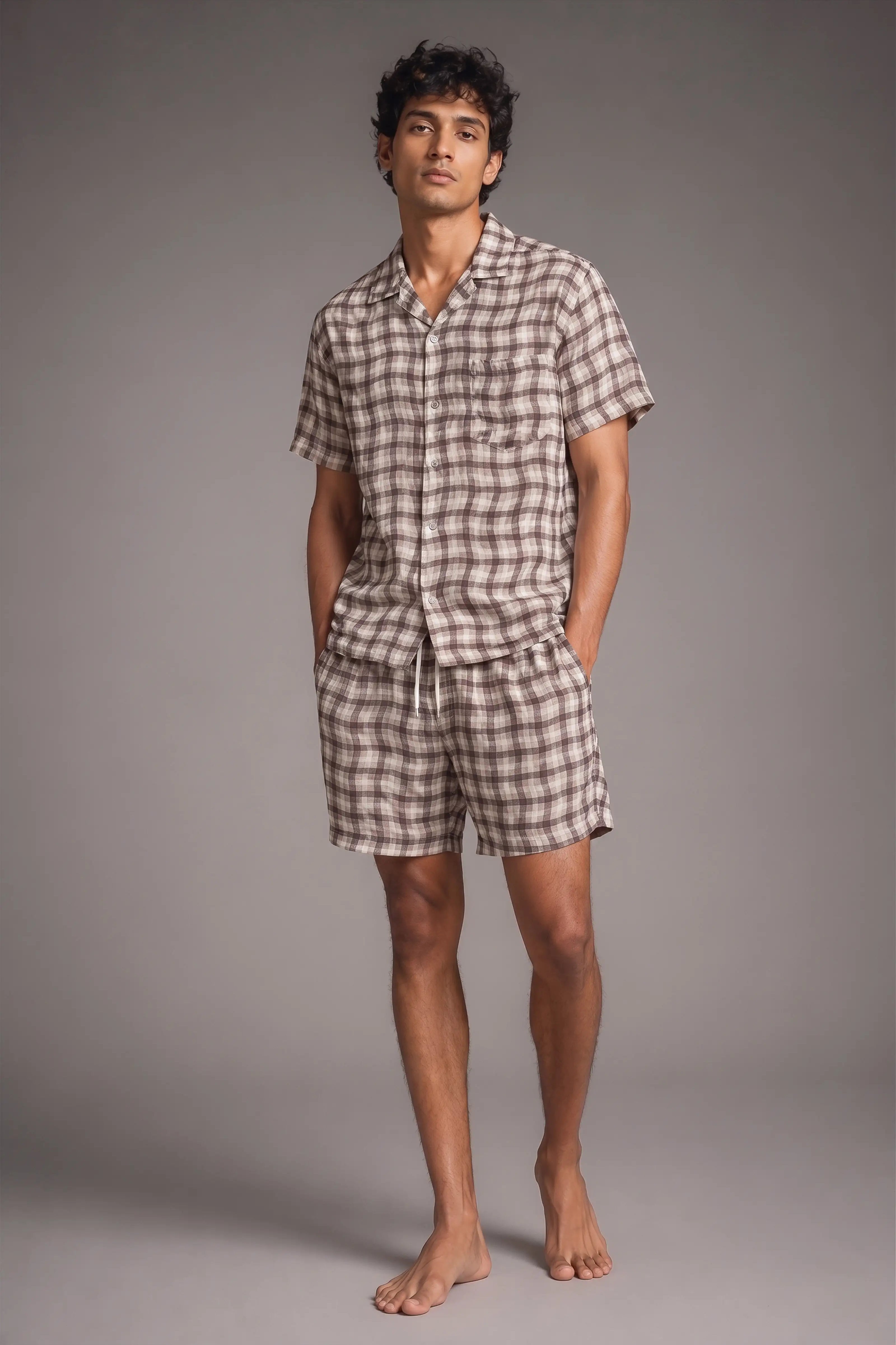 Man wearing a checkered shirt and shorts set against a gray background
