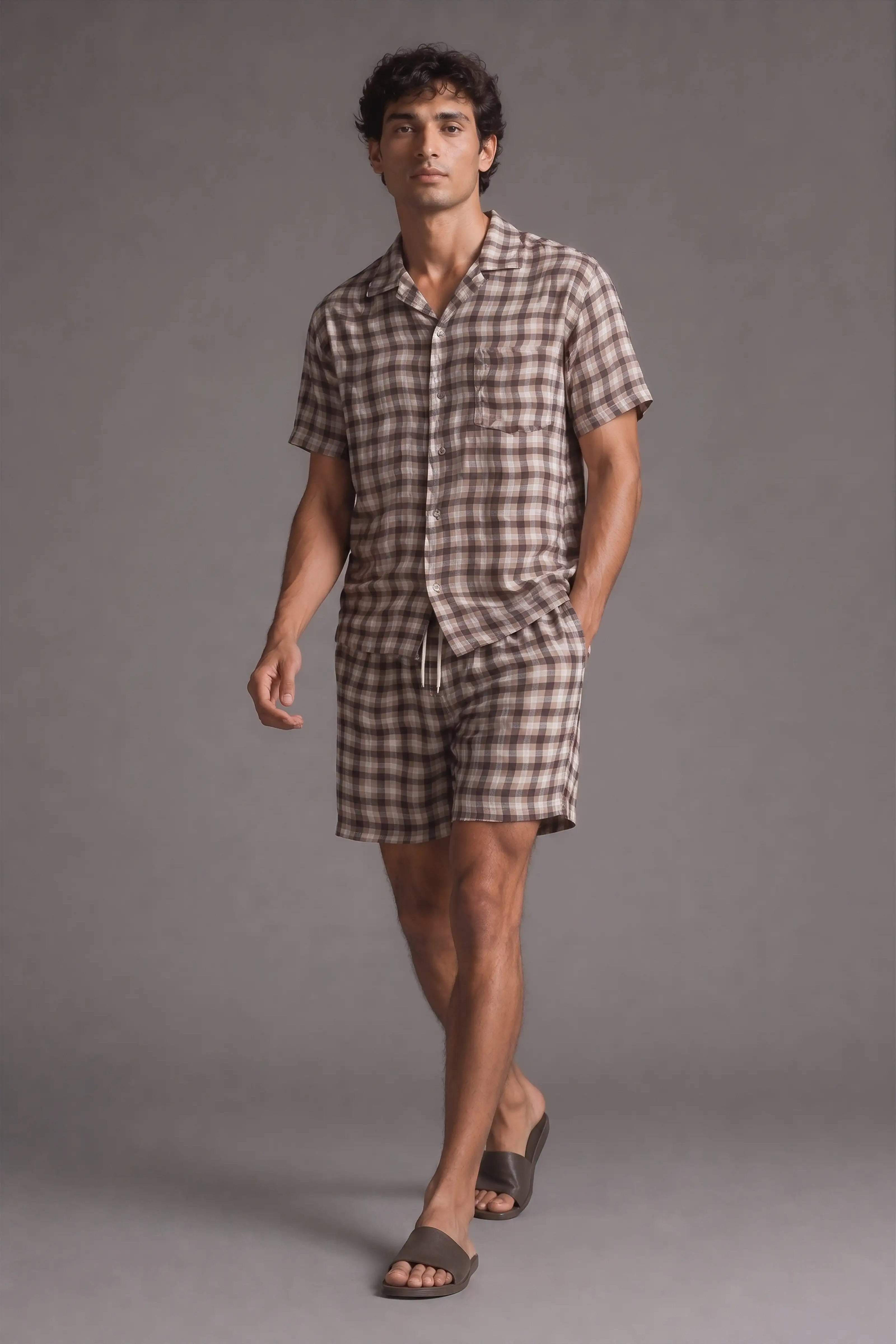 Man wearing a checkered shirt and shorts on a gray background