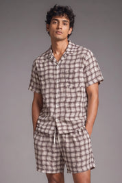 Man wearing a plaid pajama set against a gray background