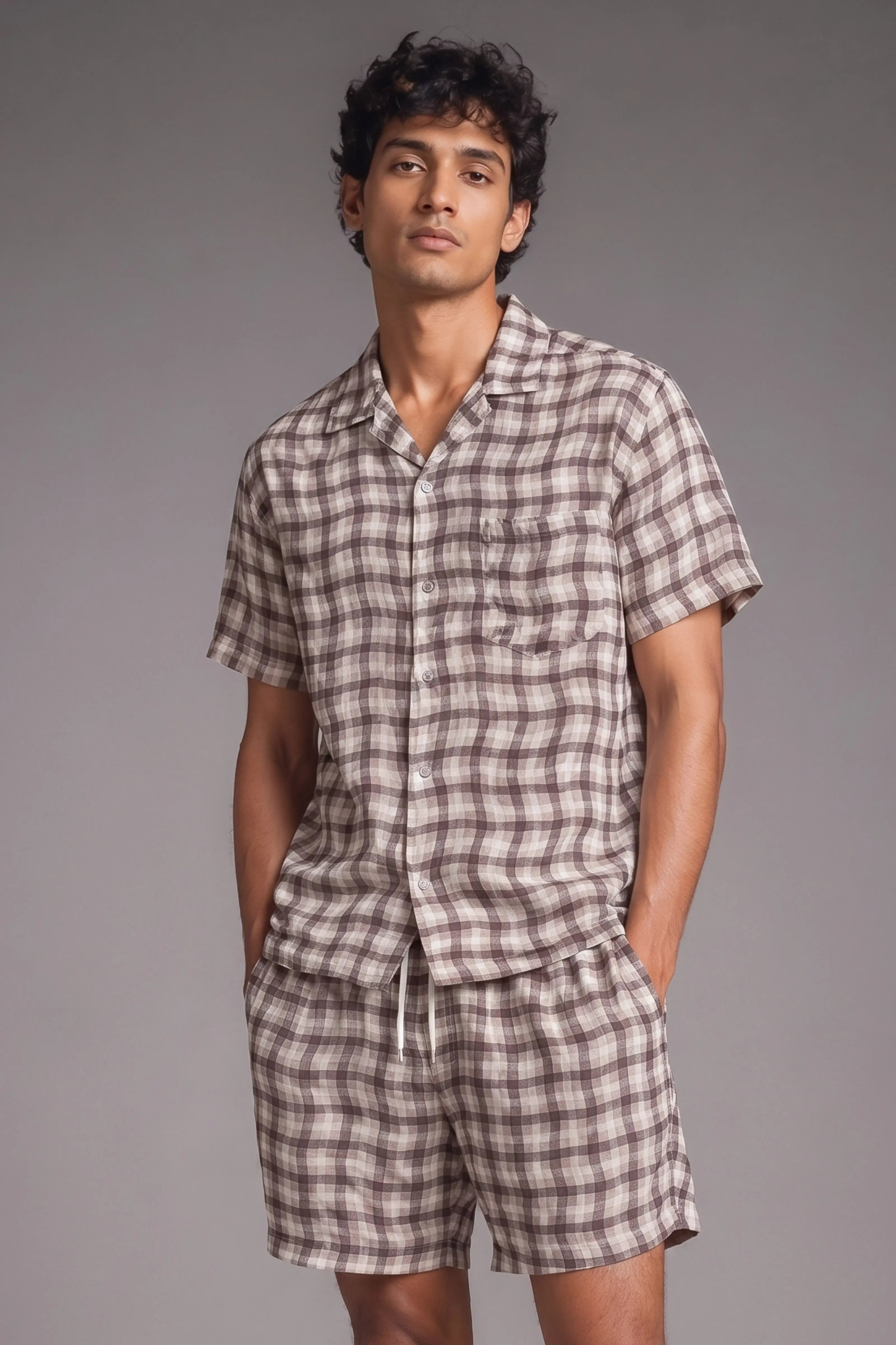 Man wearing a plaid pajama set against a gray background