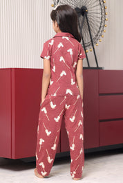 A person wearing a maroon pajama set with white pony print patterns. The girl in a room.