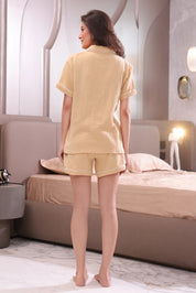 Woman wearing a beige shorts set in a bedroom.