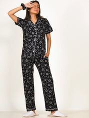 A girl wearing a black Star Moon Print Pyjama Set nightwear by NapStory, gently resting one hand on her eye and the other hand tucked away.