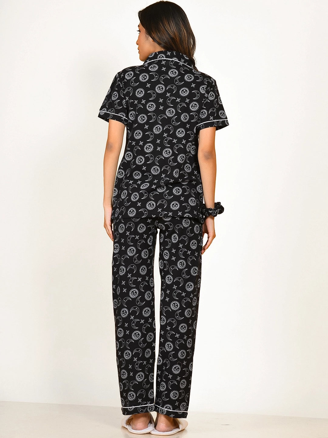 A girl in a black Star Moon Print Pyjama Set nightwear by NapStory, standing in a straight back pose.