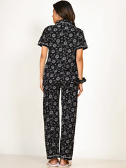 A girl in a black Star Moon Print Pyjama Set nightwear by NapStory, standing in a straight back pose.