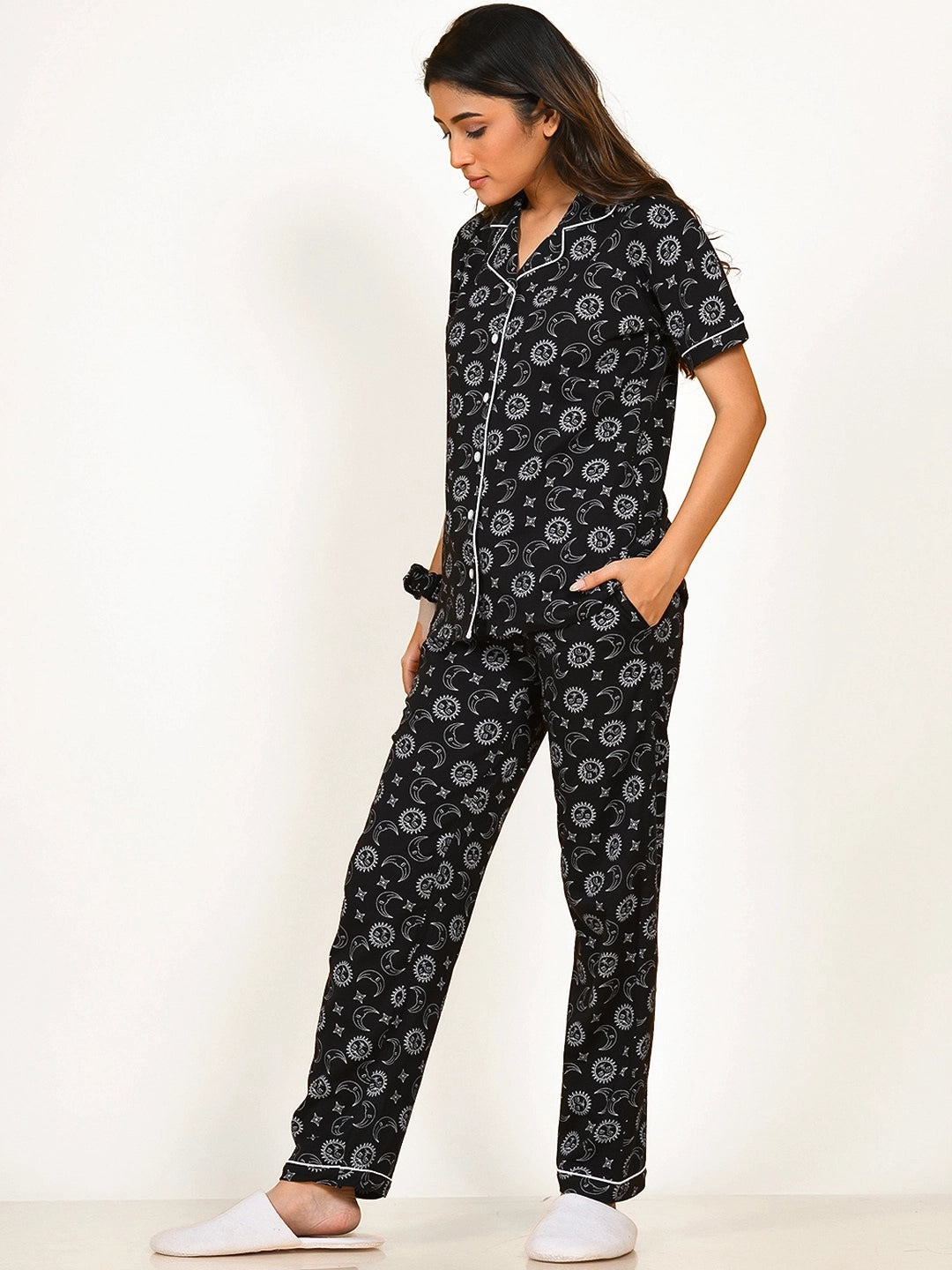 A girl in a black Star Moon Print Pyjama Set nightwear by NapStory, standing with a relaxed look.