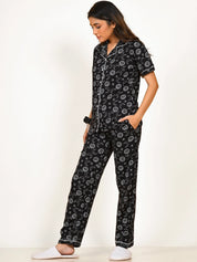A girl in a black Star Moon Print Pyjama Set nightwear by NapStory, standing with a relaxed look.