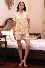 Woman wearing a yellow checkered Shorts set in a bedroom setting.