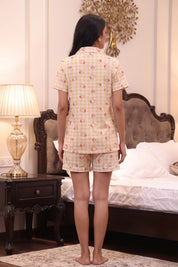 Woman wearing a yellow checkered outfit in a bedroom setting