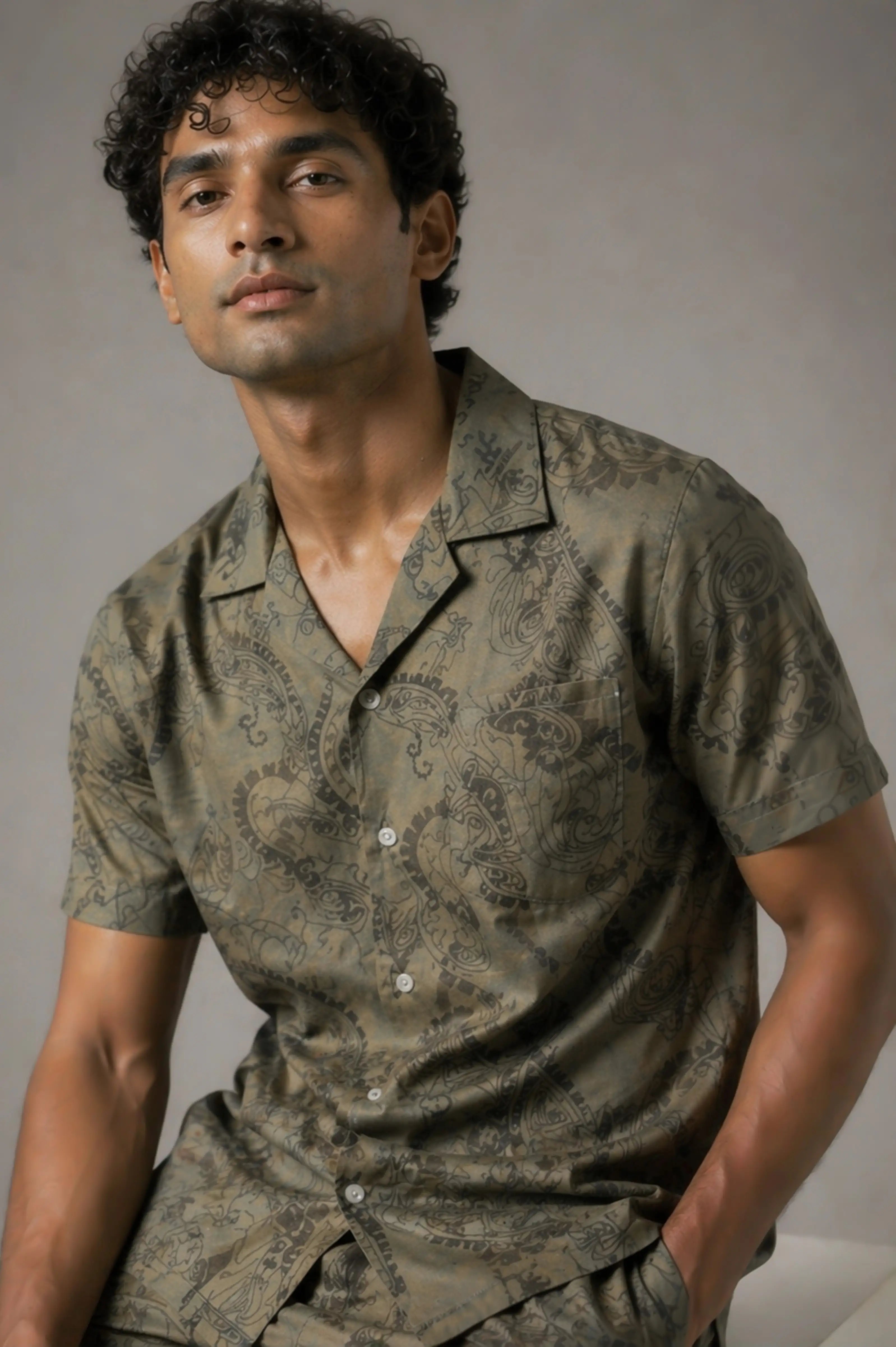 Man wearing a patterned green shirt against a neutral background