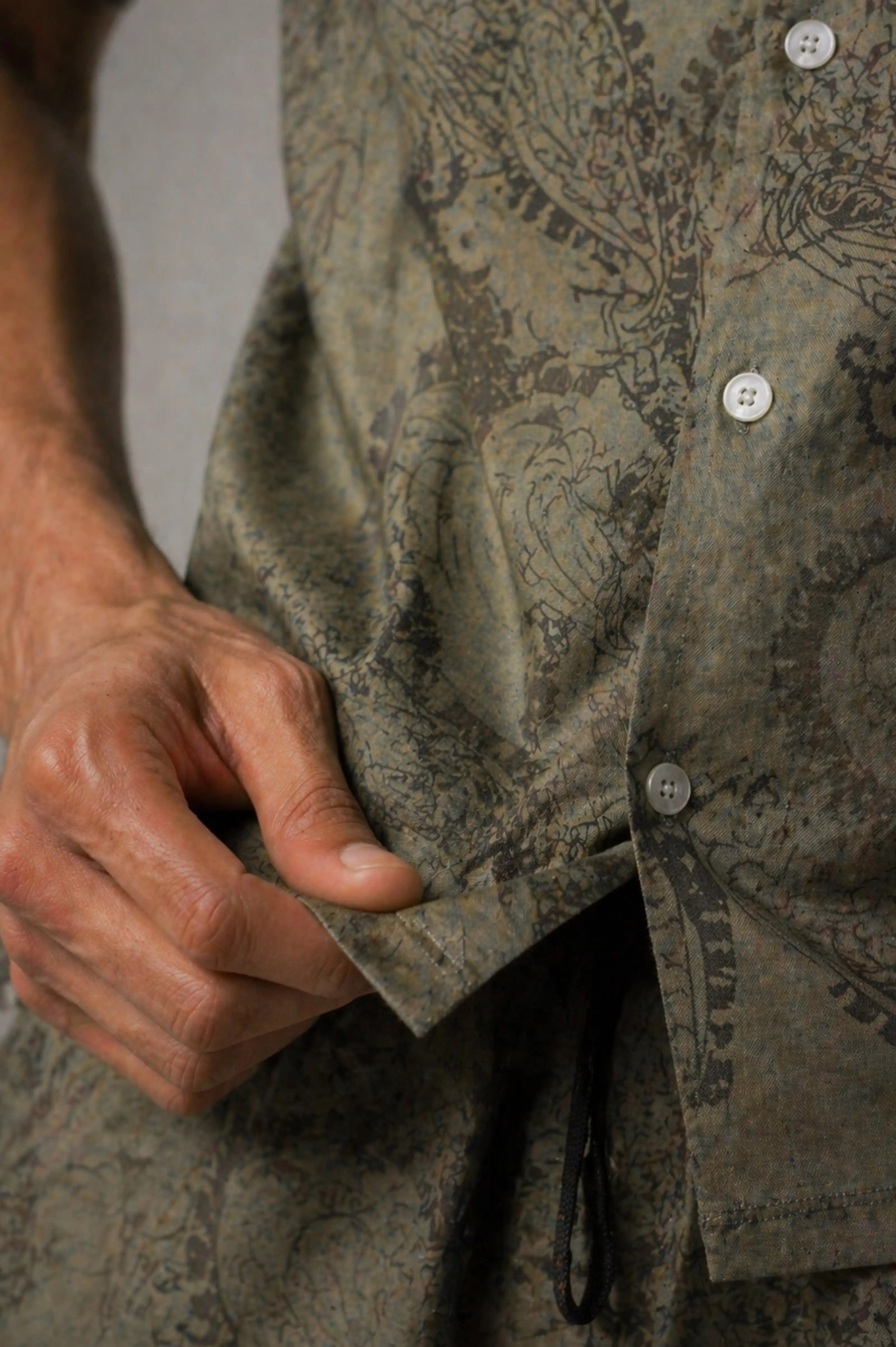 Close-up of a person wearing a patterned shirt with buttons.