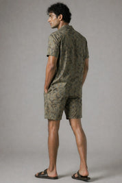 Man wearing a green camouflage outfit against a gray background
