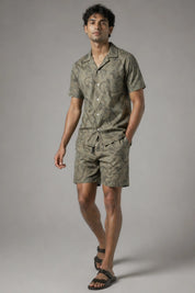 Man wearing a matching olive green shirt and shorts set on a gray background