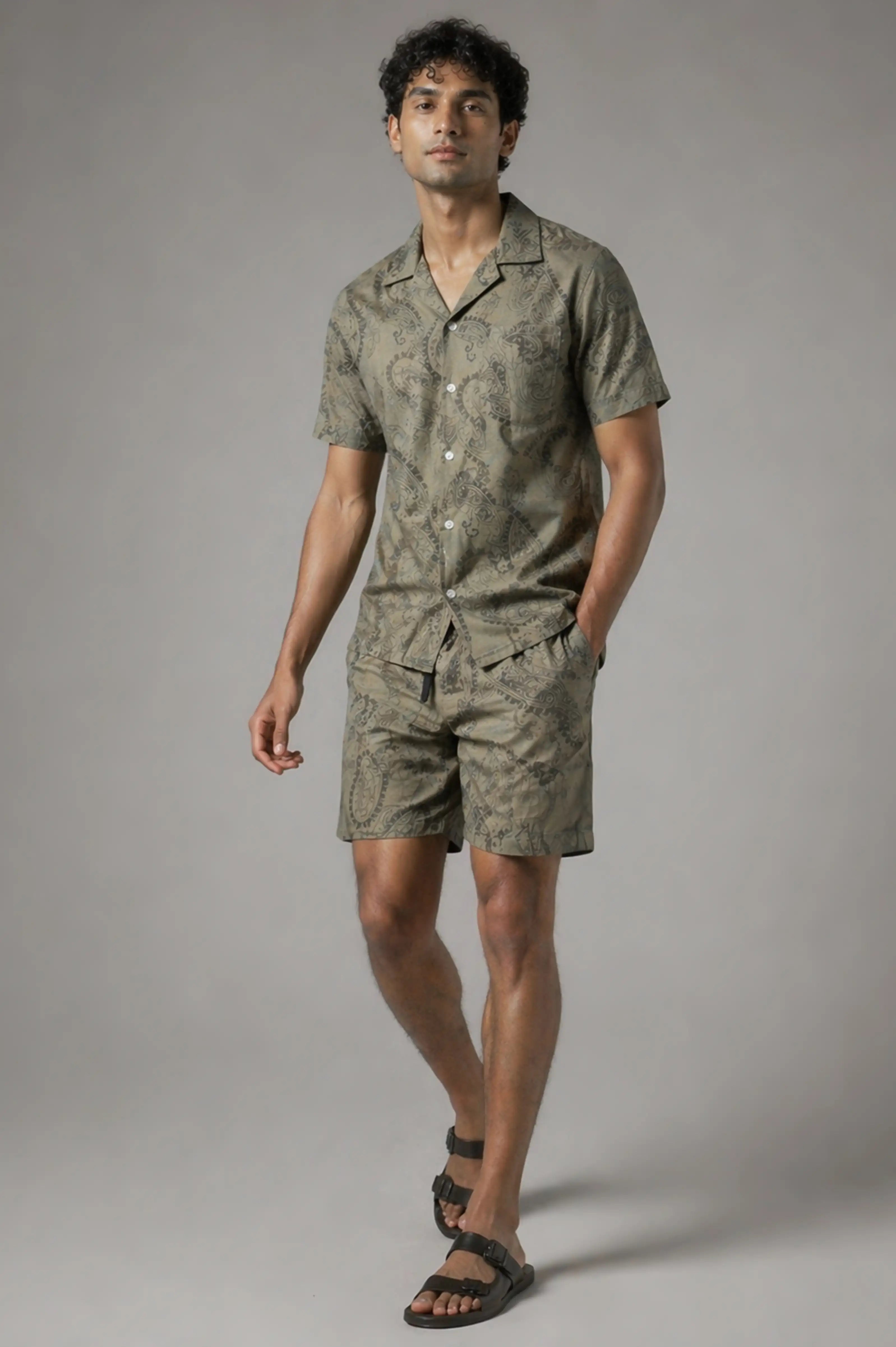 Man wearing a matching olive green shirt and shorts set on a gray background