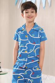 Kid wearing a blue pajama set with car patterns against a neutral background