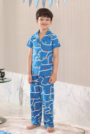 Child wearing a blue pajama set with a car pattern standing on a neutral background