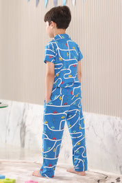 A child wearing a blue pajama set with a car pattern, standing in a back view pose in a room.