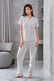 Woman wearing a white floral pajama set in a modern room.