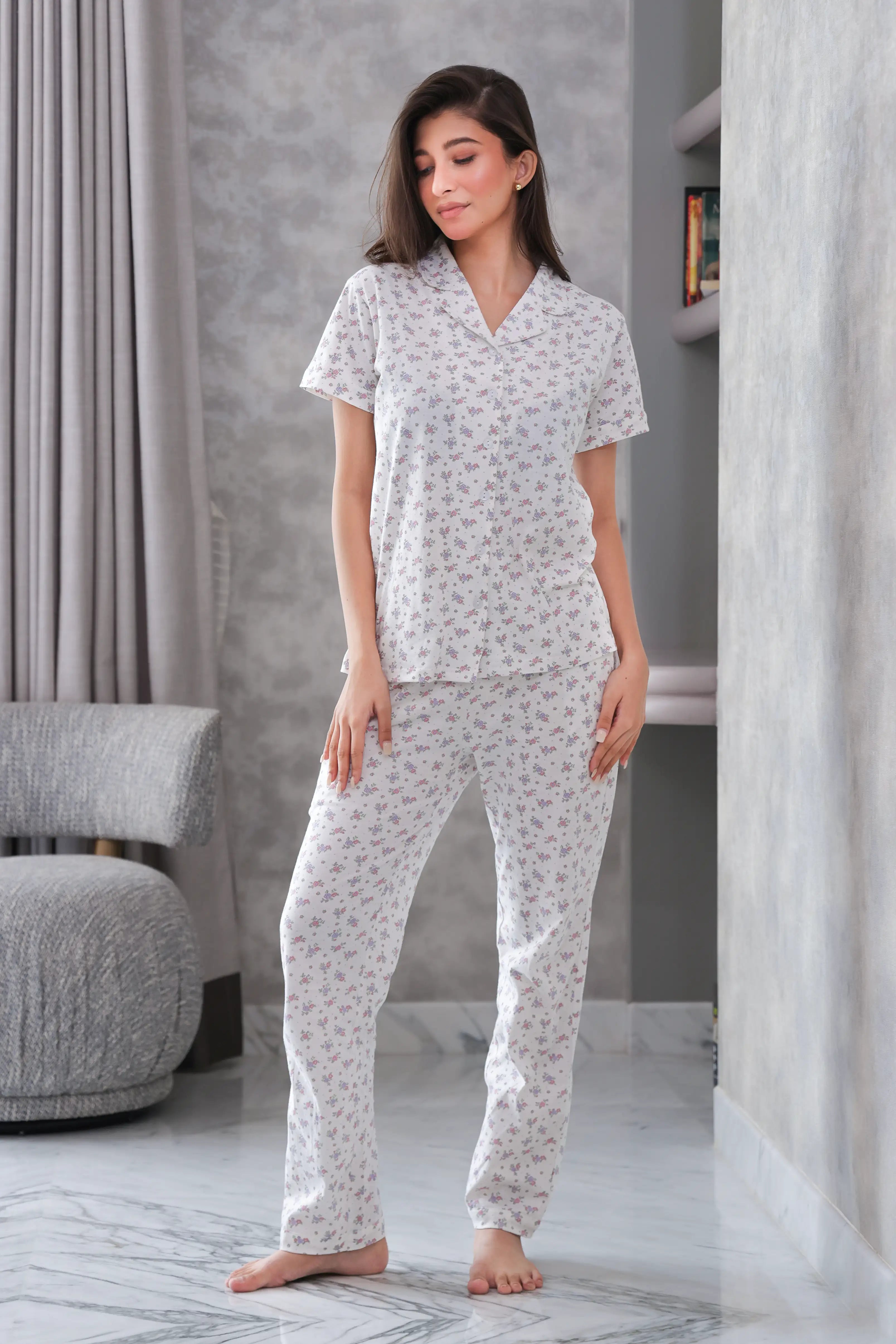 Woman wearing a white floral pajama set in a modern room.