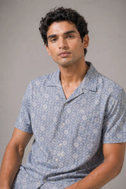 Man wearing a patterned blue shirt against a gray background