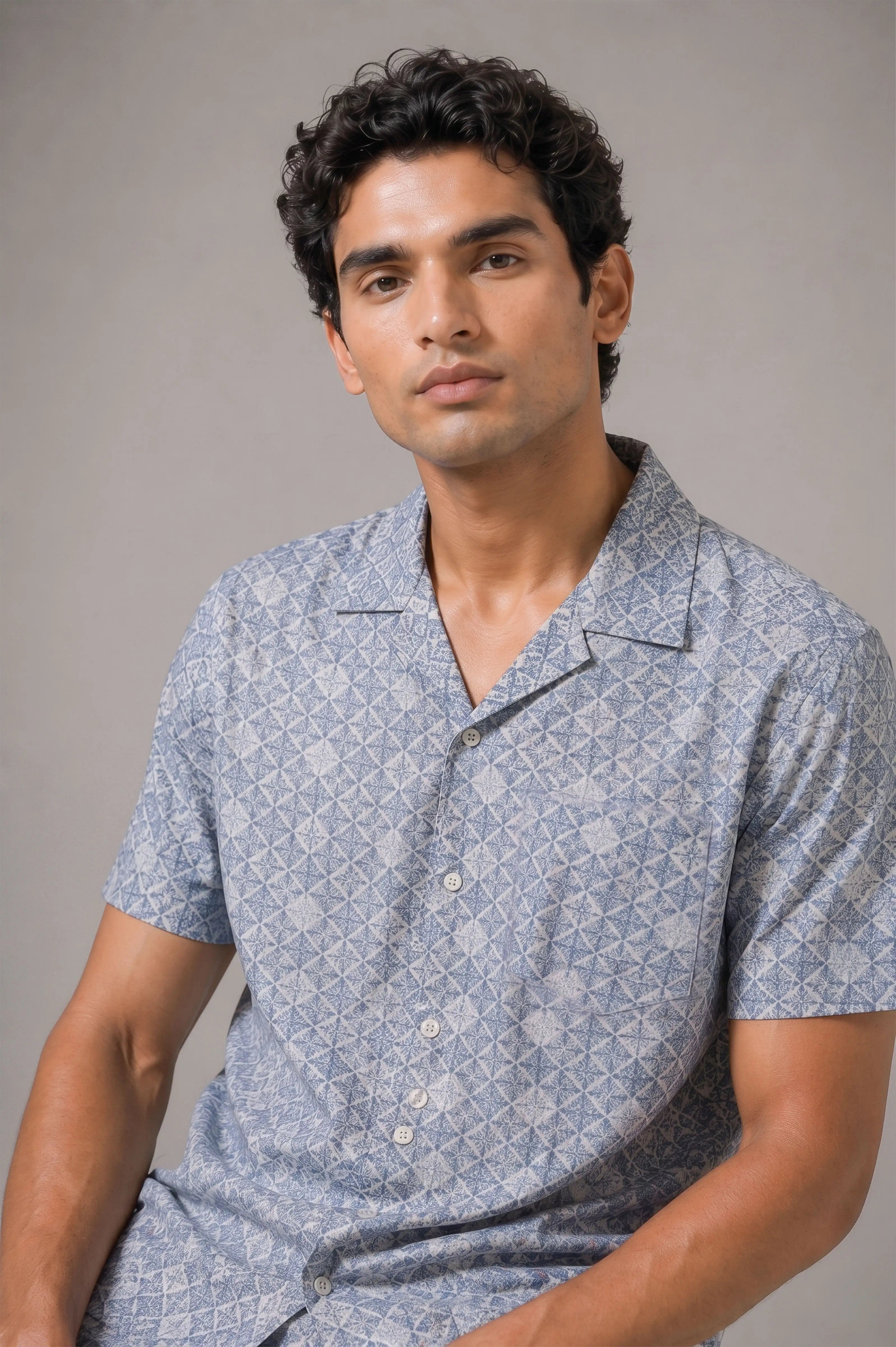 Man wearing a patterned blue shirt against a gray background