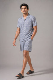 Man wearing a gray patterned pajama set on a gray background